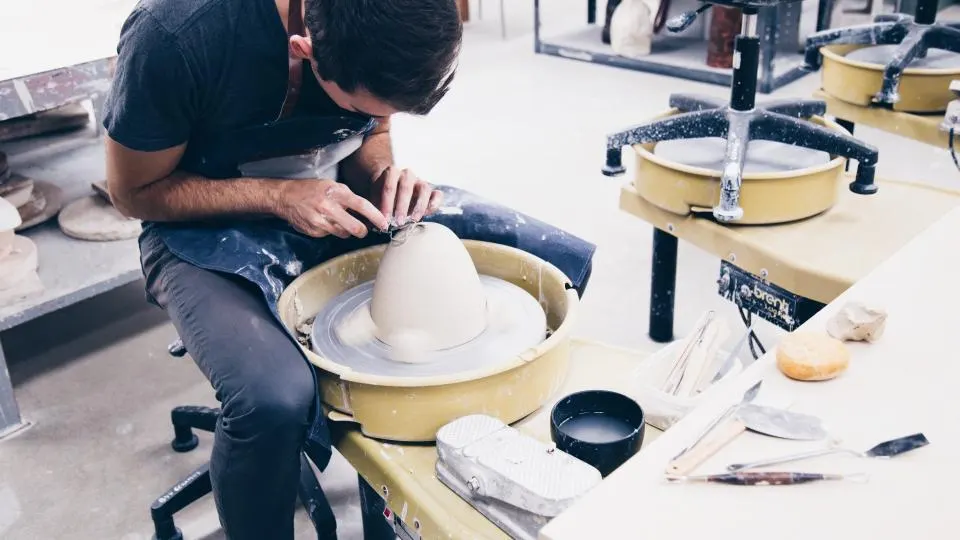 Un artisan céramiste façonne une pièce sur son tour, dans son atelier