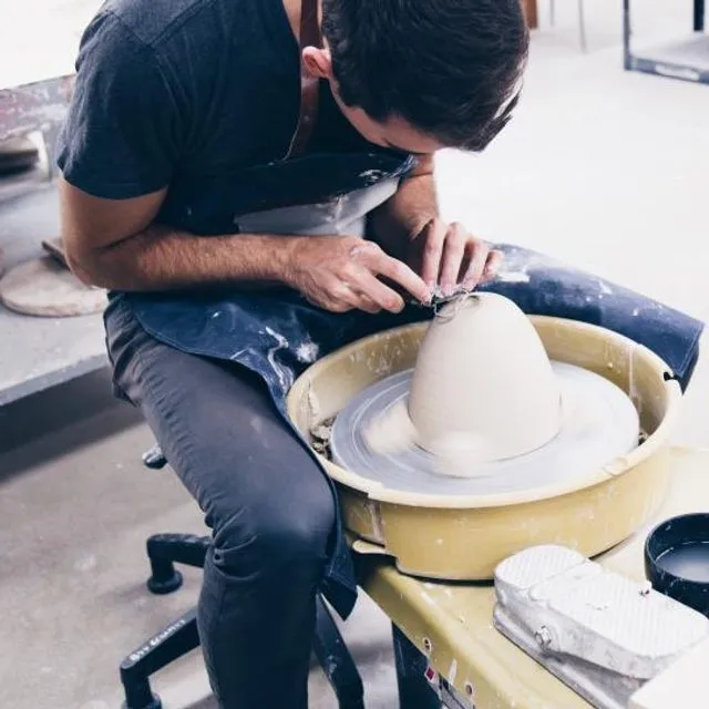 Un céramiste au travail sur son tour, dans son atelier