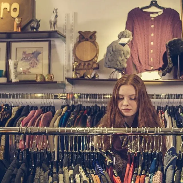 A young woman in a clothing store, between the racks